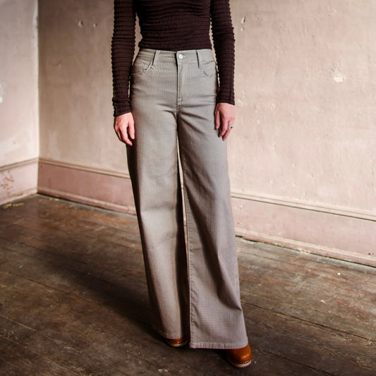 Image featuring a woman wearing the Frame Le Slim Palazzo pants in a hounds tooth brown and camel pattern.