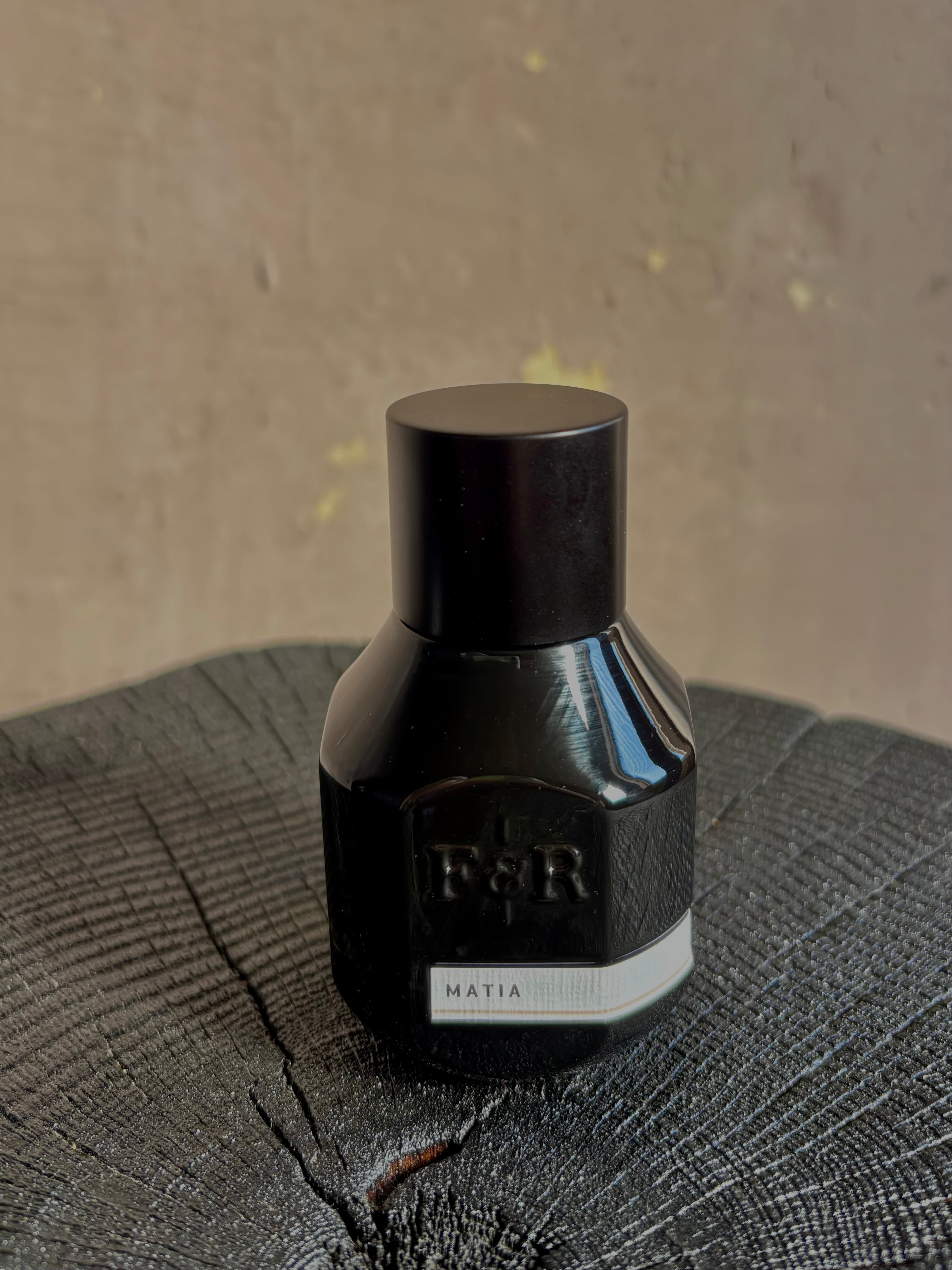 A small black bottle with a matching black cap with embossed F&R logo and a white label reading MATIA from Fulton and Roark made in USA
