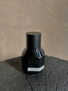 Image of  small black bottle with a matte black metal cap and a white label reading PALMETTO and F&R Monogramed Extrait de Parfum made in USA