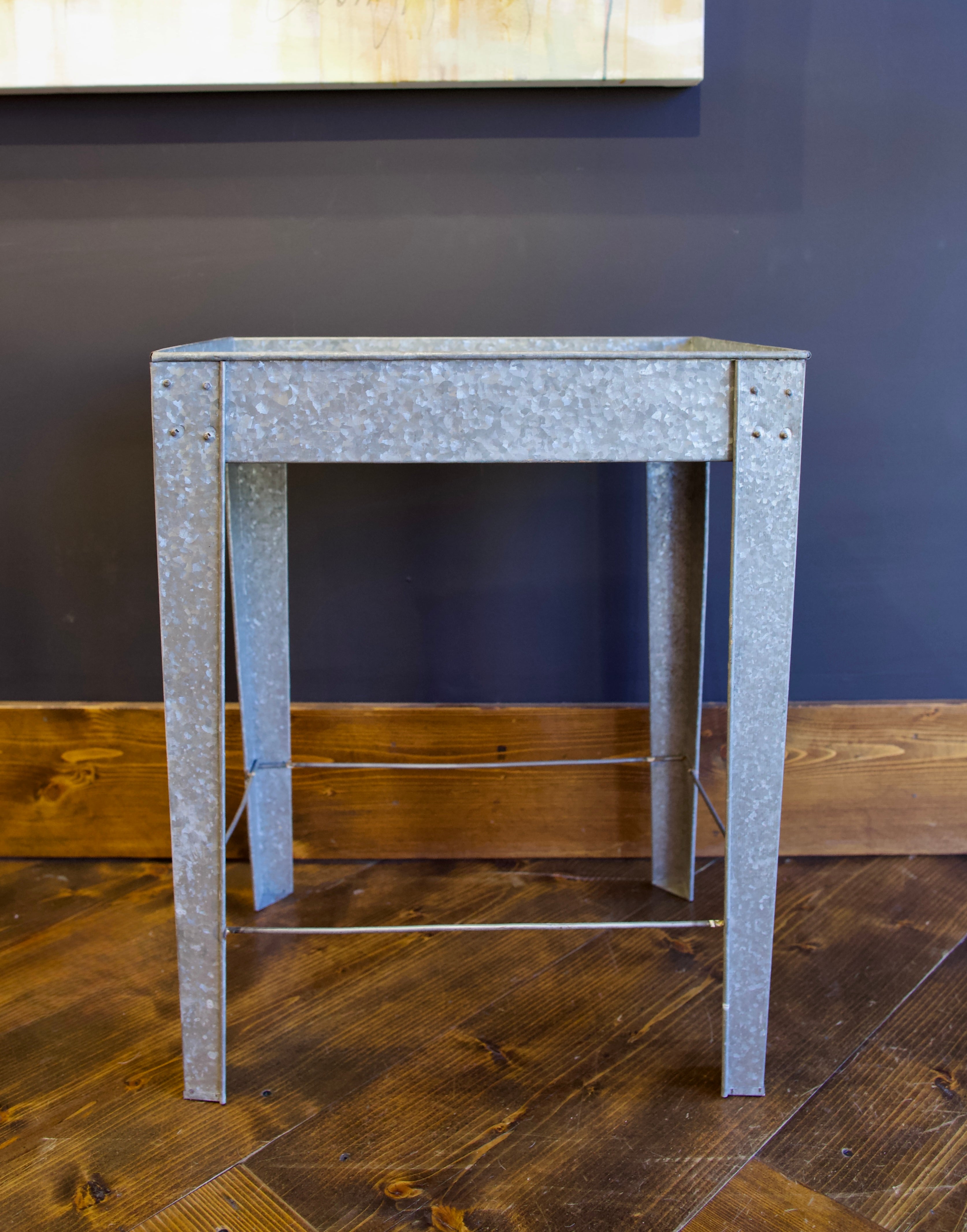 A rectangular galvanized metal tray table with side handles for indoor or outdoor versatility