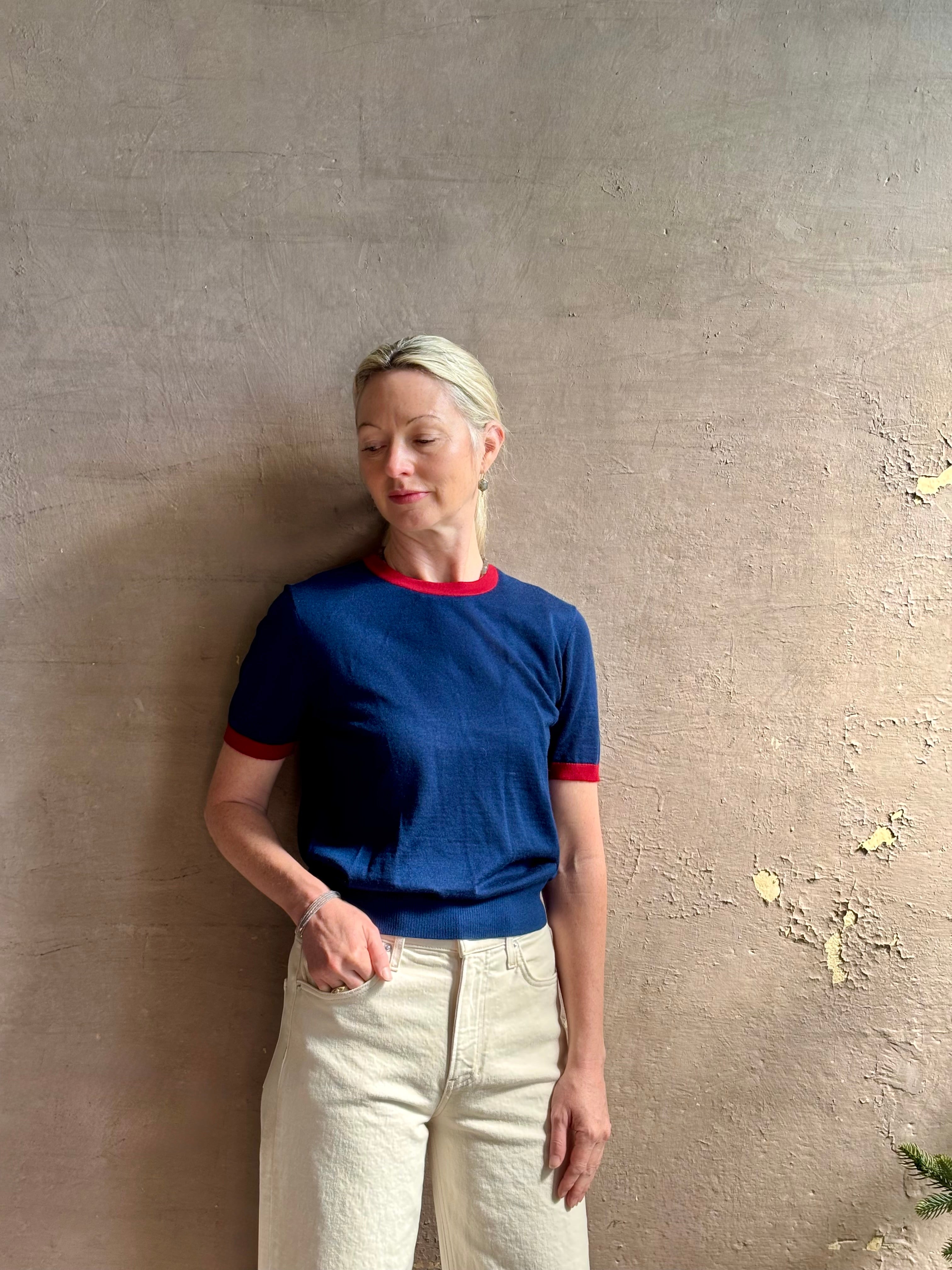 Mature woman wearing women's designer cashmere Airy short sleeve Ringer Tee from Guest in Residence rendered in a navy body with carmine ringer detailing and crafted from 100% lightweight cashmere with a crew neckline