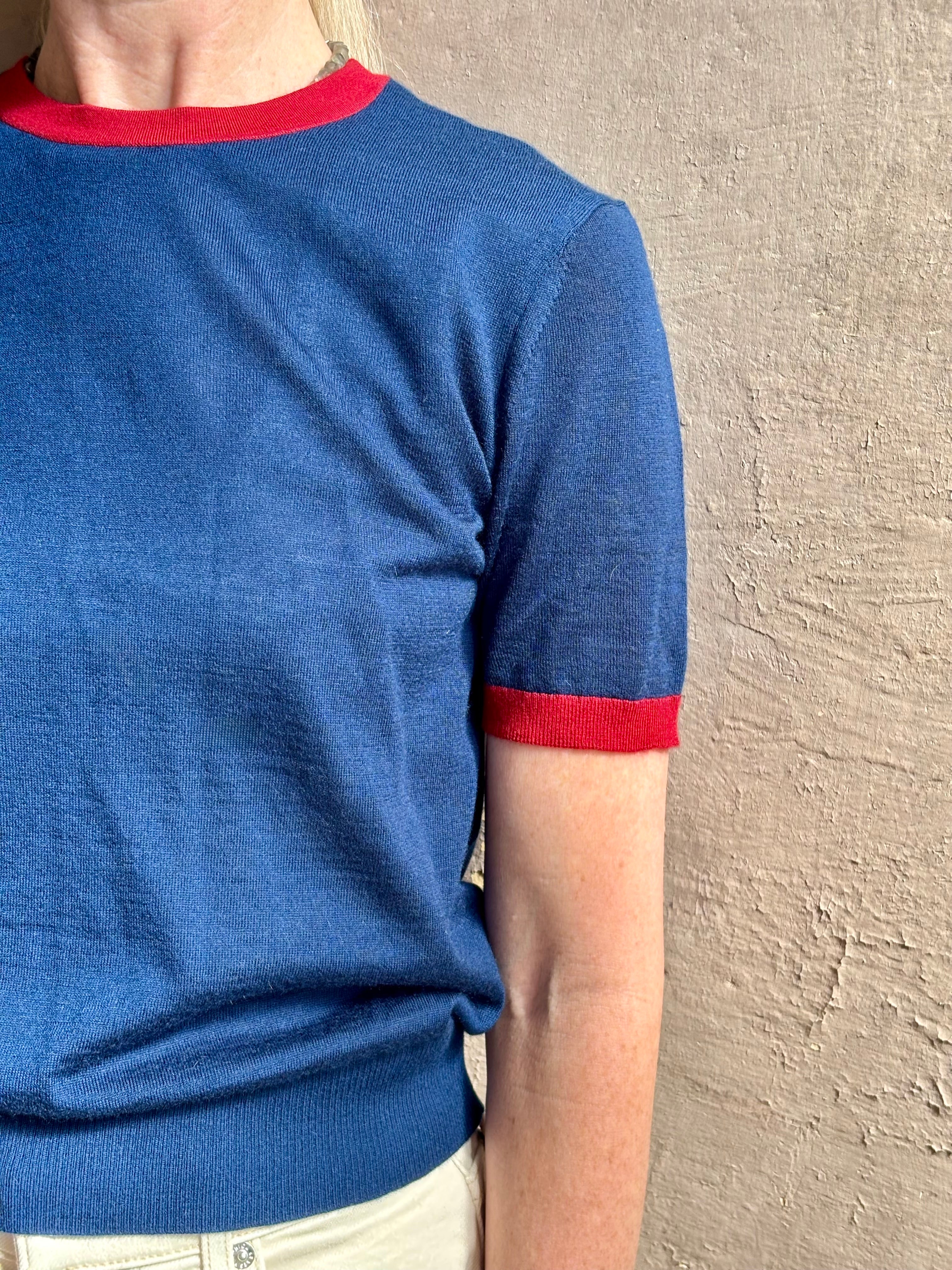 Mature woman wearing women's designer cashmere Airy short sleeve Ringer Tee from Guest in Residence rendered in a navy body with carmine ringer detailing and crafted from 100% lightweight cashmere with a crew neckline