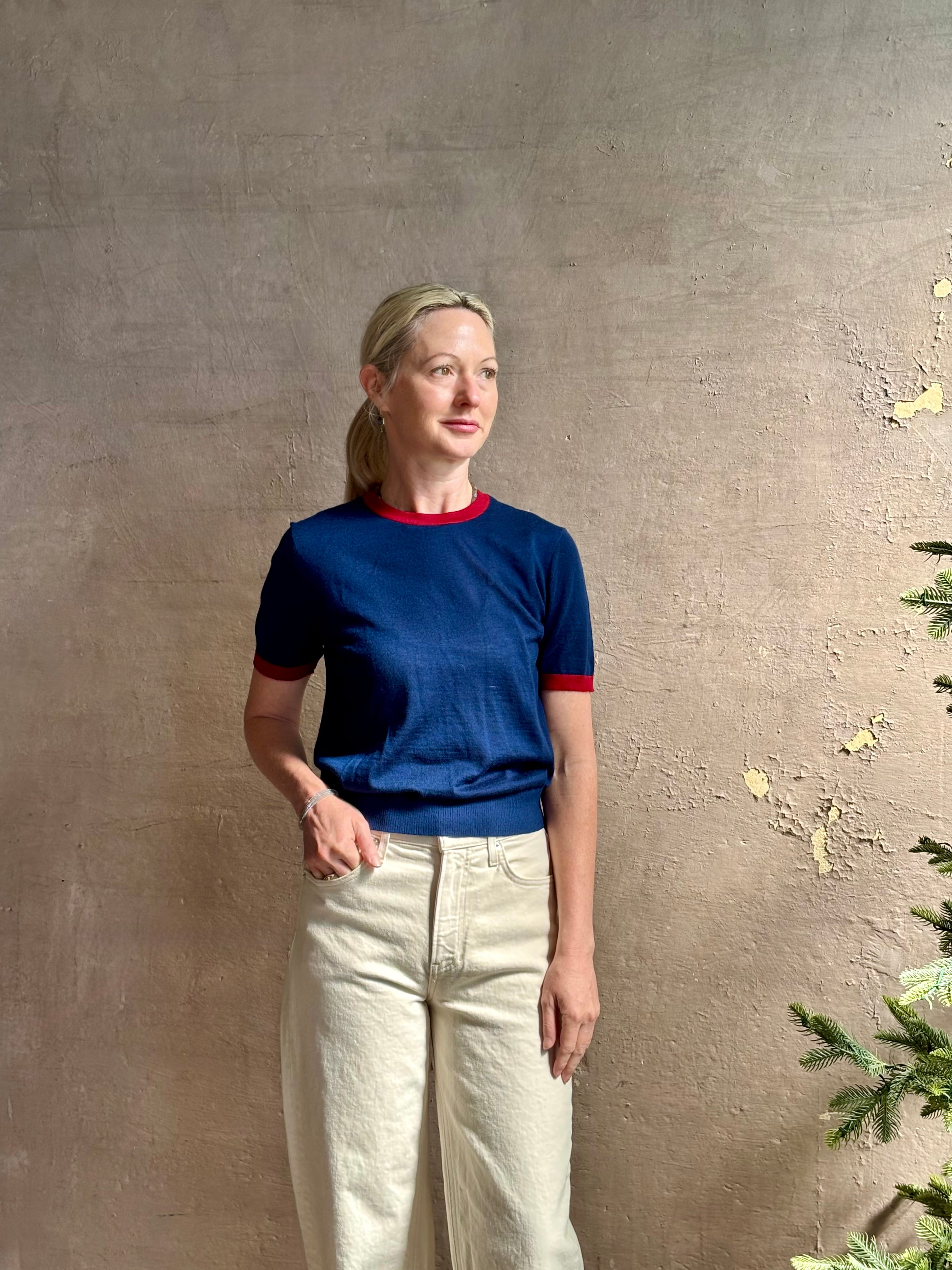 Mature woman wearing women's designer cashmere Airy short sleeve Ringer Tee from Guest in Residence rendered in a navy body with carmine ringer detailing and crafted from 100% lightweight cashmere with a crew neckline