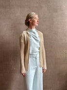 Image of mature woman wearing premium cashmere linen GUEST IN RESIDENCE Breezy Cardigan in Sandstone beige with long sleeves hook and eye front closure and ribbed texture