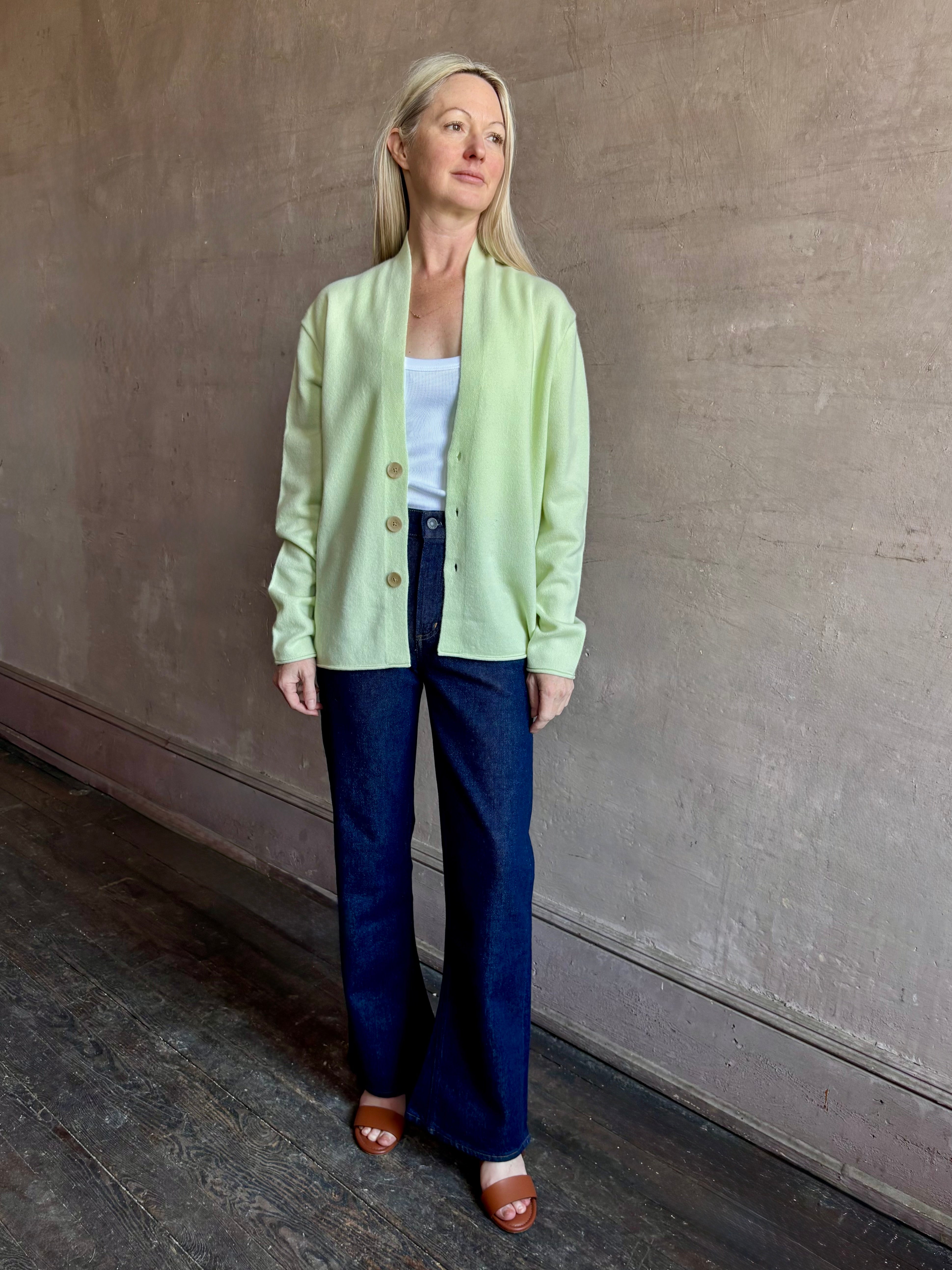 Image of mature woman wearing luxury cashmere sweater GUEST IN RESIDENCE Everywhere Cardigan in Limewash green with long sleeves and three button front v-neck