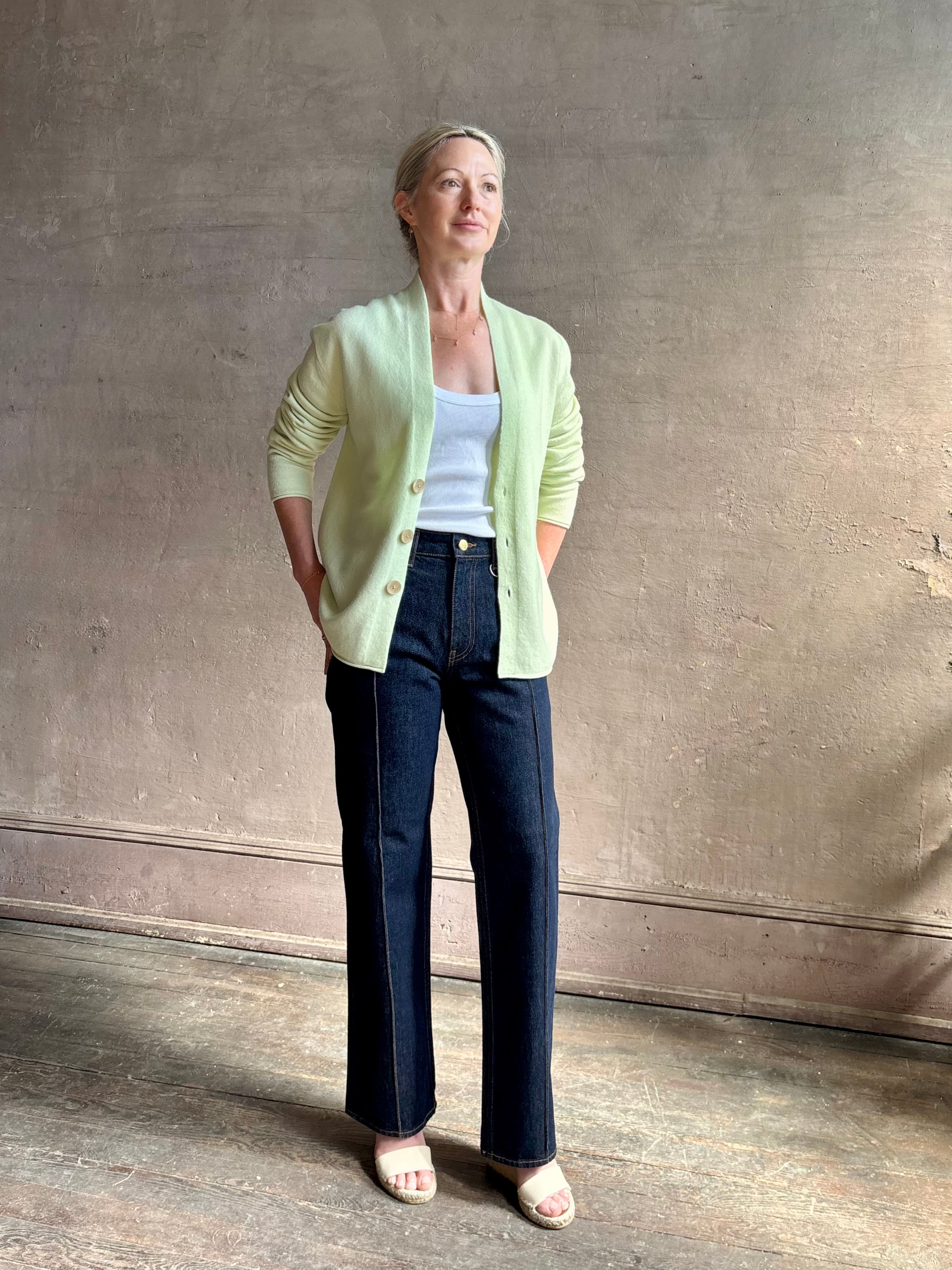 Image of mature woman wearing luxury cashmere sweater GUEST IN RESIDENCE Everywhere Cardigan in Limewash green with long sleeves and three button front v-neck