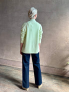 Image of mature woman wearing luxury cashmere sweater GUEST IN RESIDENCE Everywhere Cardigan in Limewash green with long sleeves and three button front v-neck