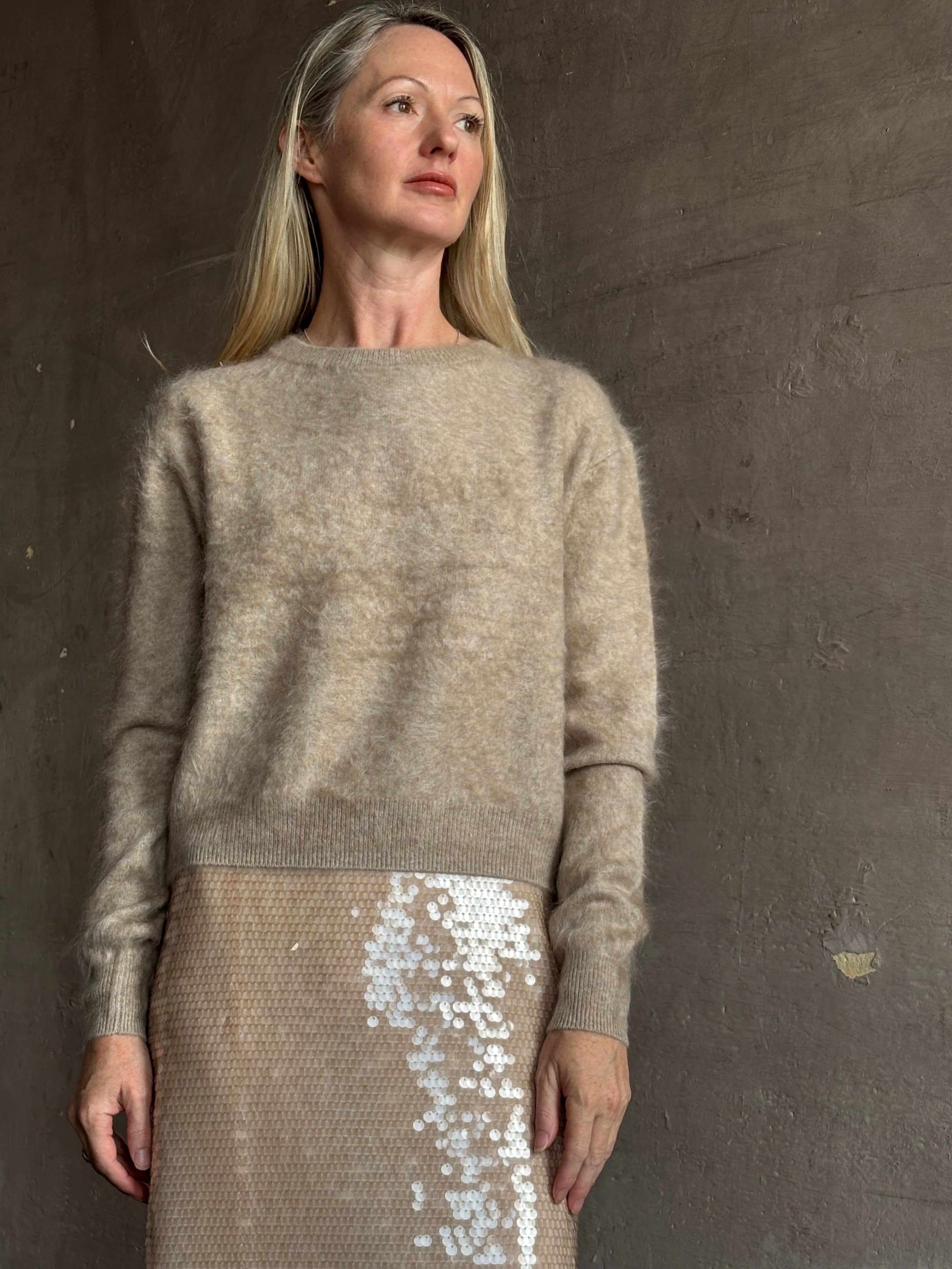 Image of mature model wearing New York luxury women's clothing brand Guest In Residence long-sleeve crew neck brushed cashmere beige sweater