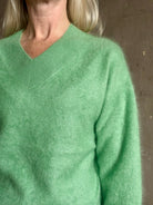 Mature woman wearing Guest in Residence Grizzly Double V Sweater Highland Green brushed cashmere with symmetrical front-and-back V-necklines