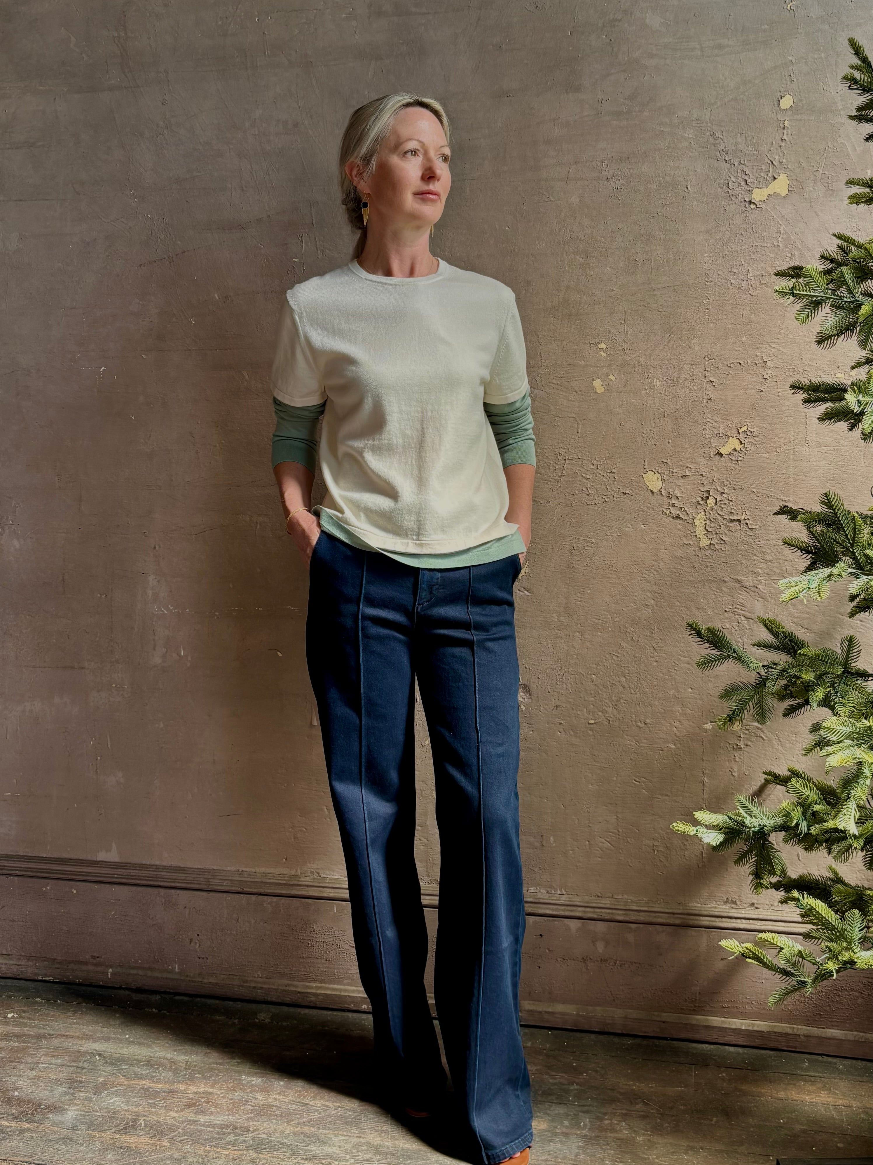 Mature woman wearing elevated luxury Layer Tee Shirt from Guest in Residence rendered in a soft sage brush green and cream colorway and crafted from an exceptional blend of cotton, cashmere, and silk with long sleeves and a crew neckline