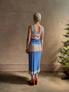 Mature woman wearing Plaited Rib knit pencil Skirt from Guest in Residence rendered in delft blue and crafted from a luxurious blend of silk, linen, nylon, and elastane with wide rib texture down front and back with pink and yellow horizontal stripes at hips and bottom edge