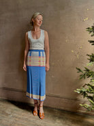 Mature woman wearing Plaited Rib knit pencil Skirt from Guest in Residence rendered in delft blue and crafted from a luxurious blend of silk, linen, nylon, and elastane with wide rib texture down front and back with pink and yellow horizontal stripes at hips and bottom edge