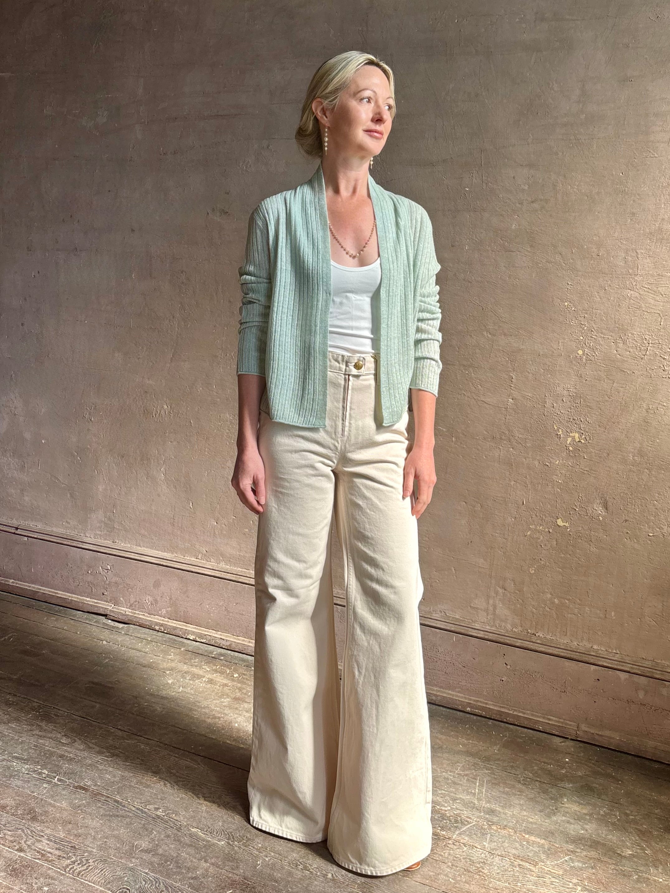 Mature woman wearing Rib Stealth Cardigan from Guest in Residence rendered in a serene sage brush aqua green and crafted from a refined blend of 58% cashmere and 42% linen with long sleeves and a hidden hook and eye closure