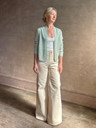 Mature woman wearing Rib Stealth Cardigan from Guest in Residence rendered in a serene sage brush aqua green and crafted from a refined blend of 58% cashmere and 42% linen with long sleeves and a hidden hook and eye closure