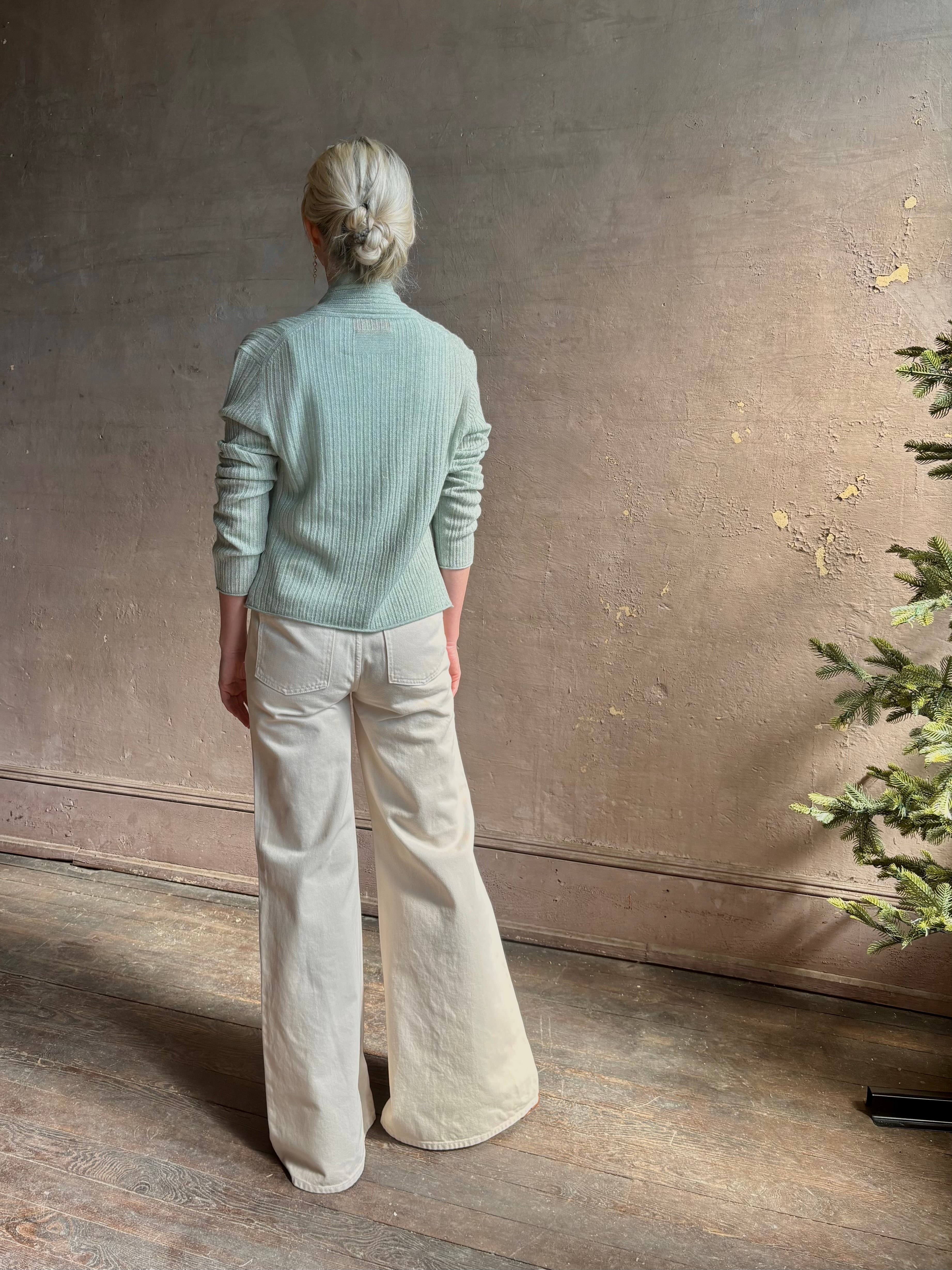 Mature woman wearing Rib Stealth Cardigan from Guest in Residence rendered in a serene sage brush aqua green and crafted from a refined blend of 58% cashmere and 42% linen with long sleeves and a hidden hook and eye closure