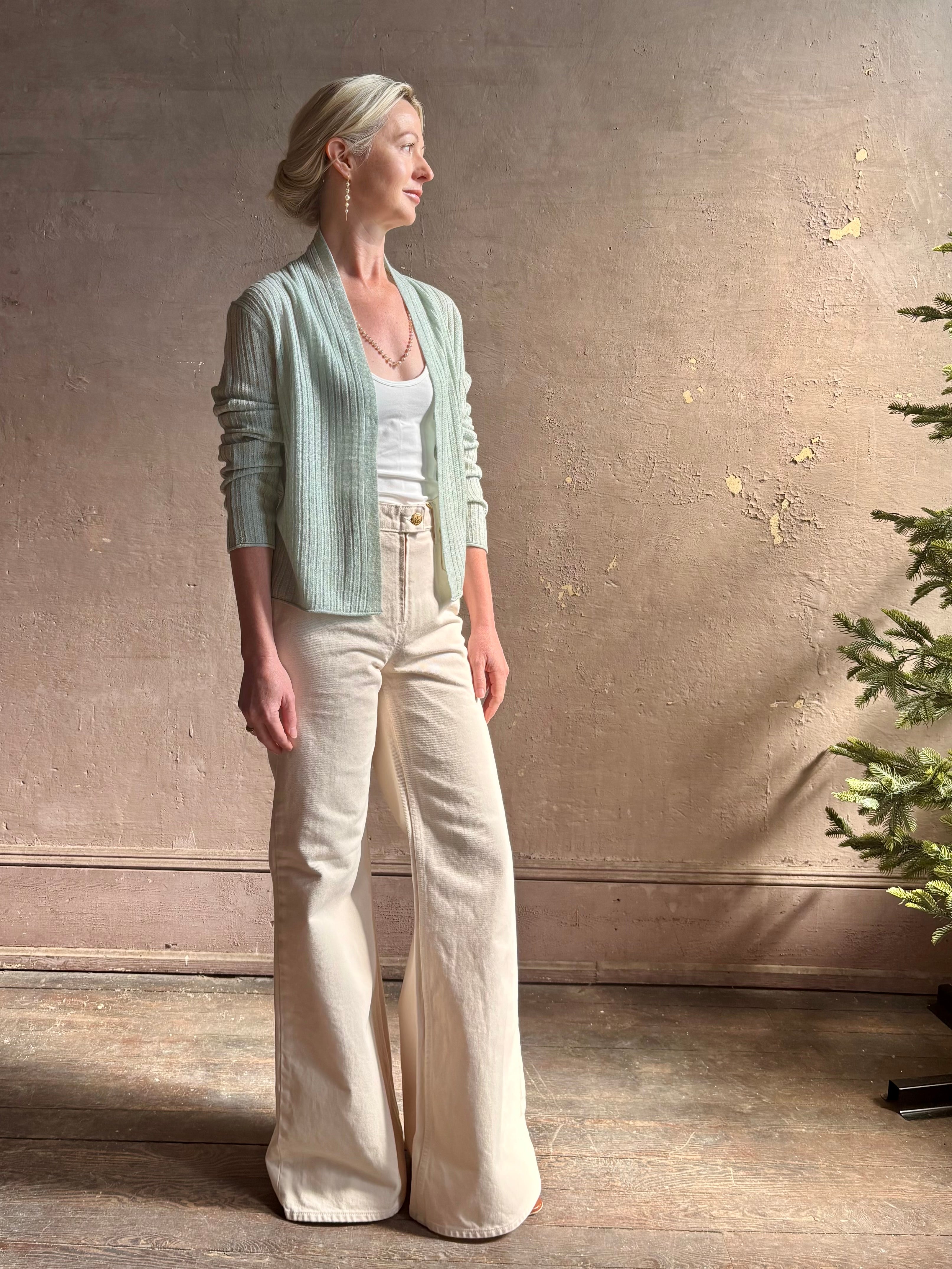 Mature woman wearing Rib Stealth Cardigan from Guest in Residence rendered in a serene sage brush aqua green and crafted from a refined blend of 58% cashmere and 42% linen with long sleeves and a hidden hook and eye closure