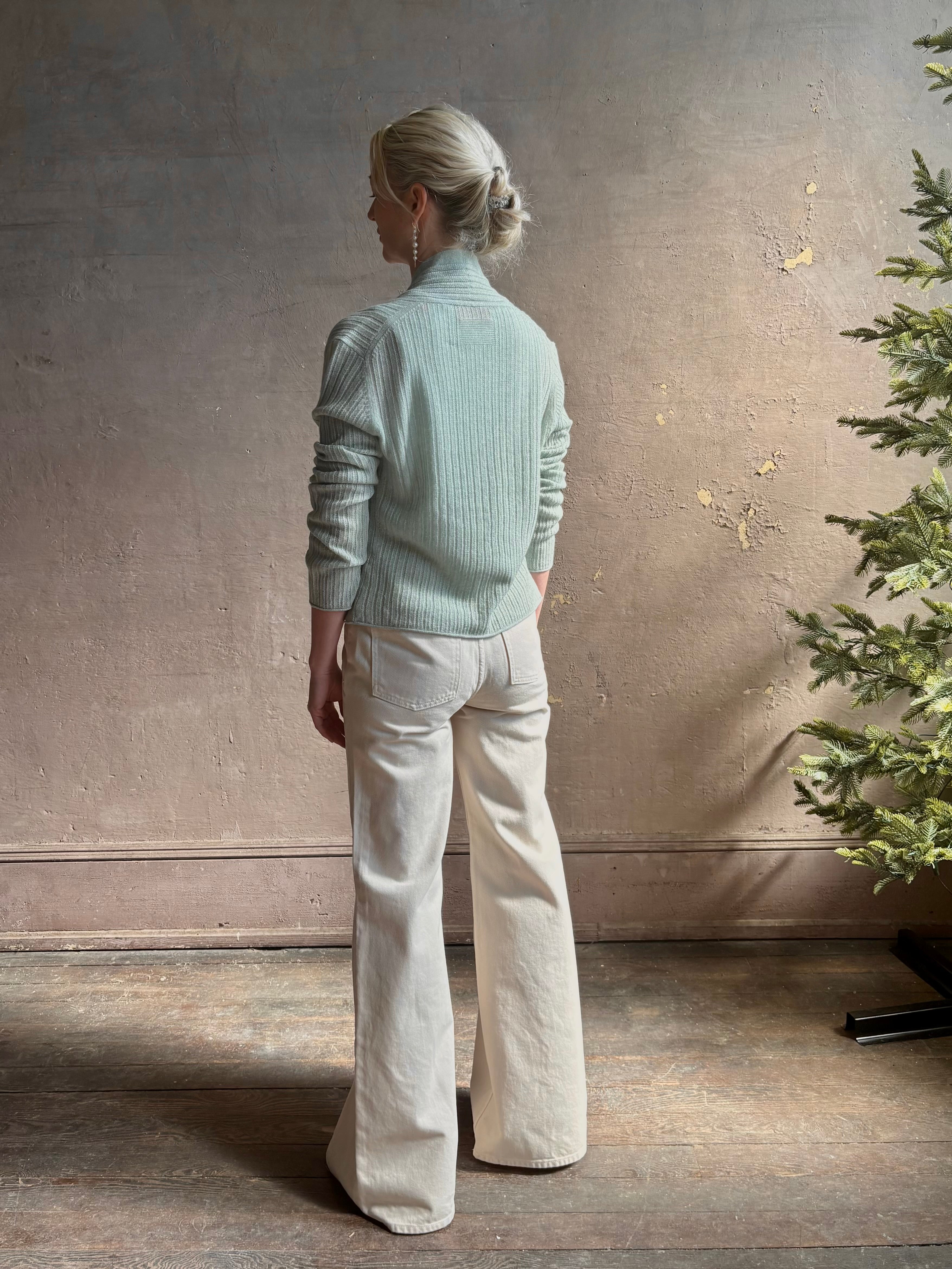Mature woman wearing Rib Stealth Cardigan from Guest in Residence rendered in a serene sage brush aqua green and crafted from a refined blend of 58% cashmere and 42% linen with long sleeves and a hidden hook and eye closure