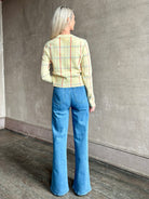 Image of woman wearing designer Guest in Residence yellow combo sweater with cable texture and subtle red, blue and beige plaid stripes pattern