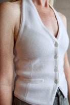 Detail image of model wearing a white cashmere halter top vest with veronica beard rigid gray denim