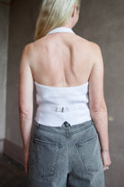 Back of model wearing a white cashmere halter top vest with veronica beard rigid gray denim