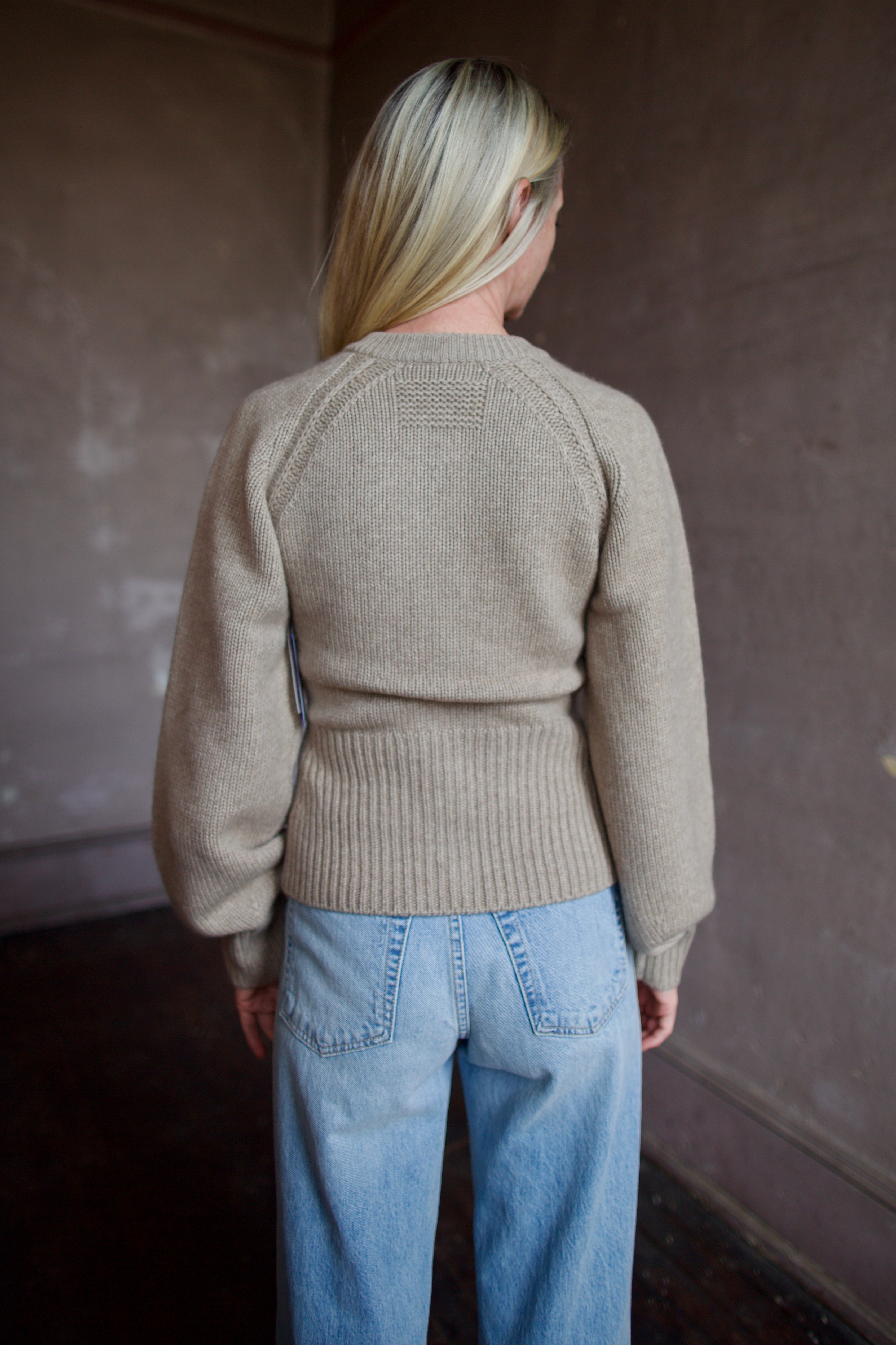 Back of model wearing a beige Guest in Residence cashmere cardigan with Slvrlake denim 