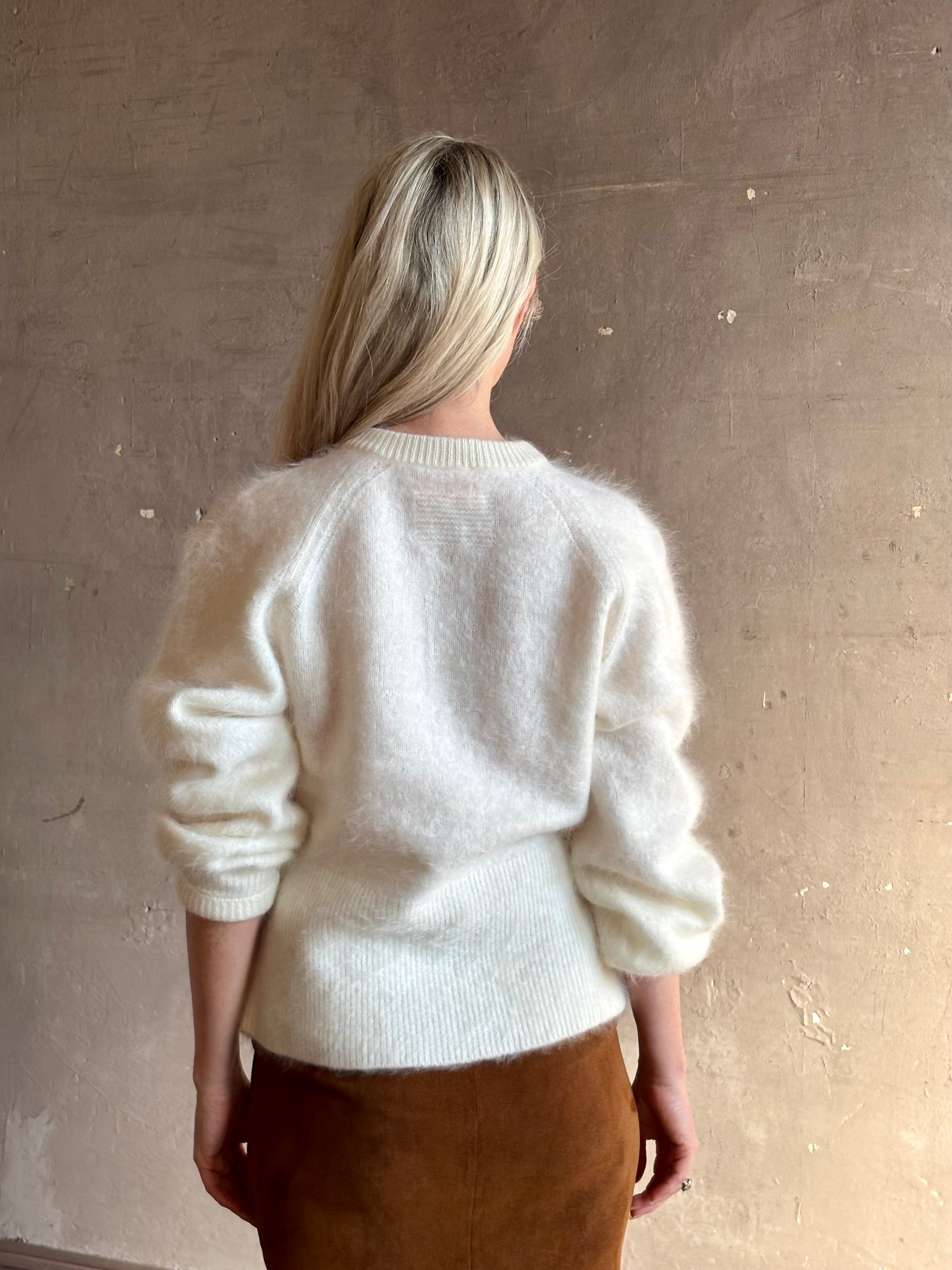 Back image of a Mature woman wearing Guest in Residence’s Grizzly Sculptured Cream brushed cashmere cardigan with crew neck fitted ribbed waistband and  henley style long sleeves