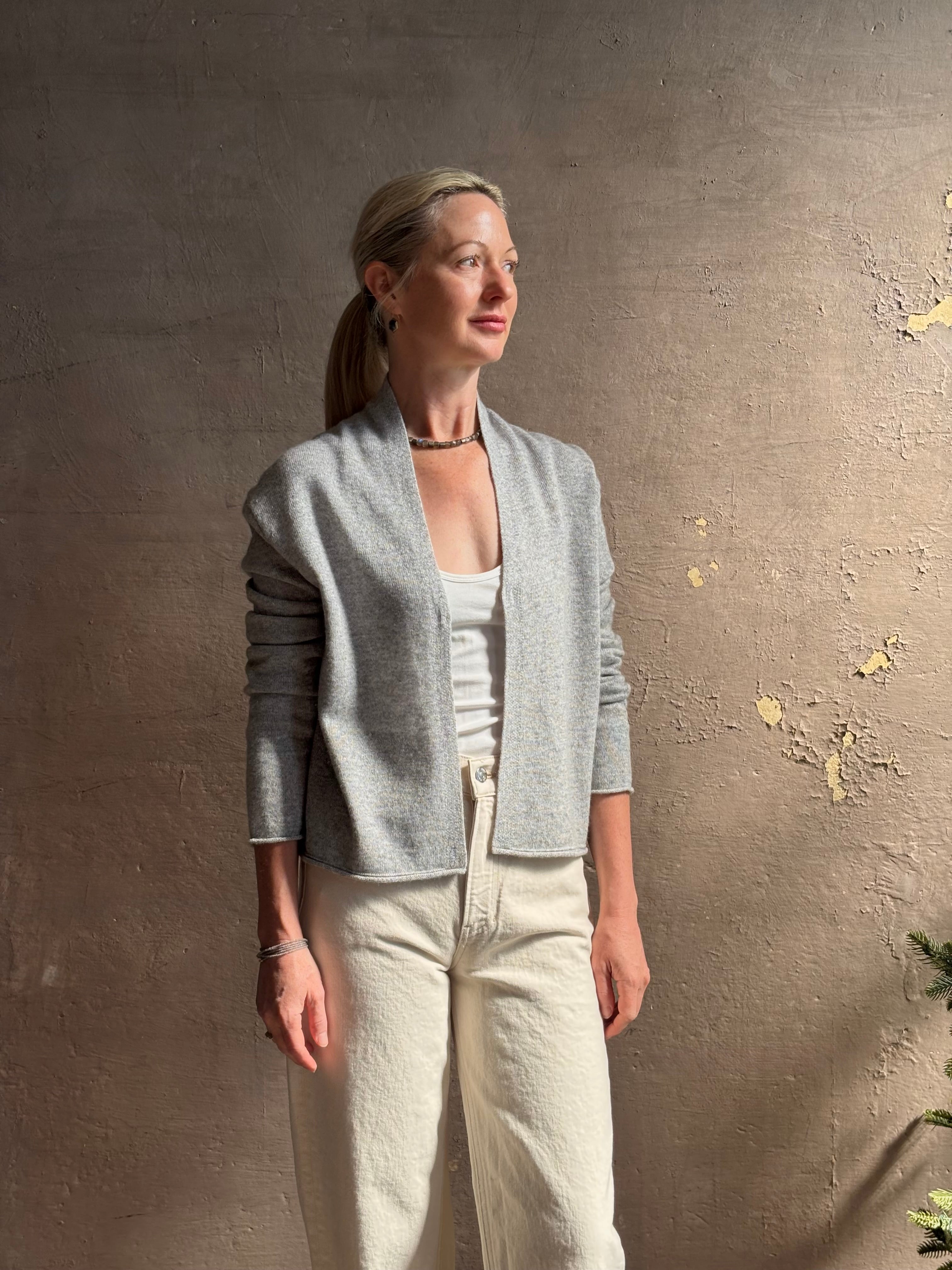 Mature woman wearing comfortable stone grey cashmere linen GUEST IN RESIDENCE Stealth long sleeve crop Cardigan with single hook and eye front closure crafted in a neutral stone grey