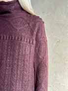 Close-up of a woman wearing a textured cable knit turtleneck sweater in a fig purple Guest in Residence Super Cloud T Neck cashmere-silk cloud-soft warmth
