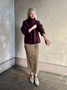 Mature woman wearing Guest in Residence’s Super Cloud T Neck in Fig cashmere-silk boucle knit with cable pattern and funnel neck