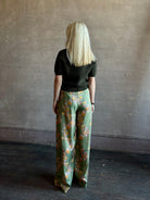 Mature woman wearing Hannah Artwear Azra silk Pant Khaki habotai with vibrant pomegranate print relaxed straight leg Fluid artisan-printed 
