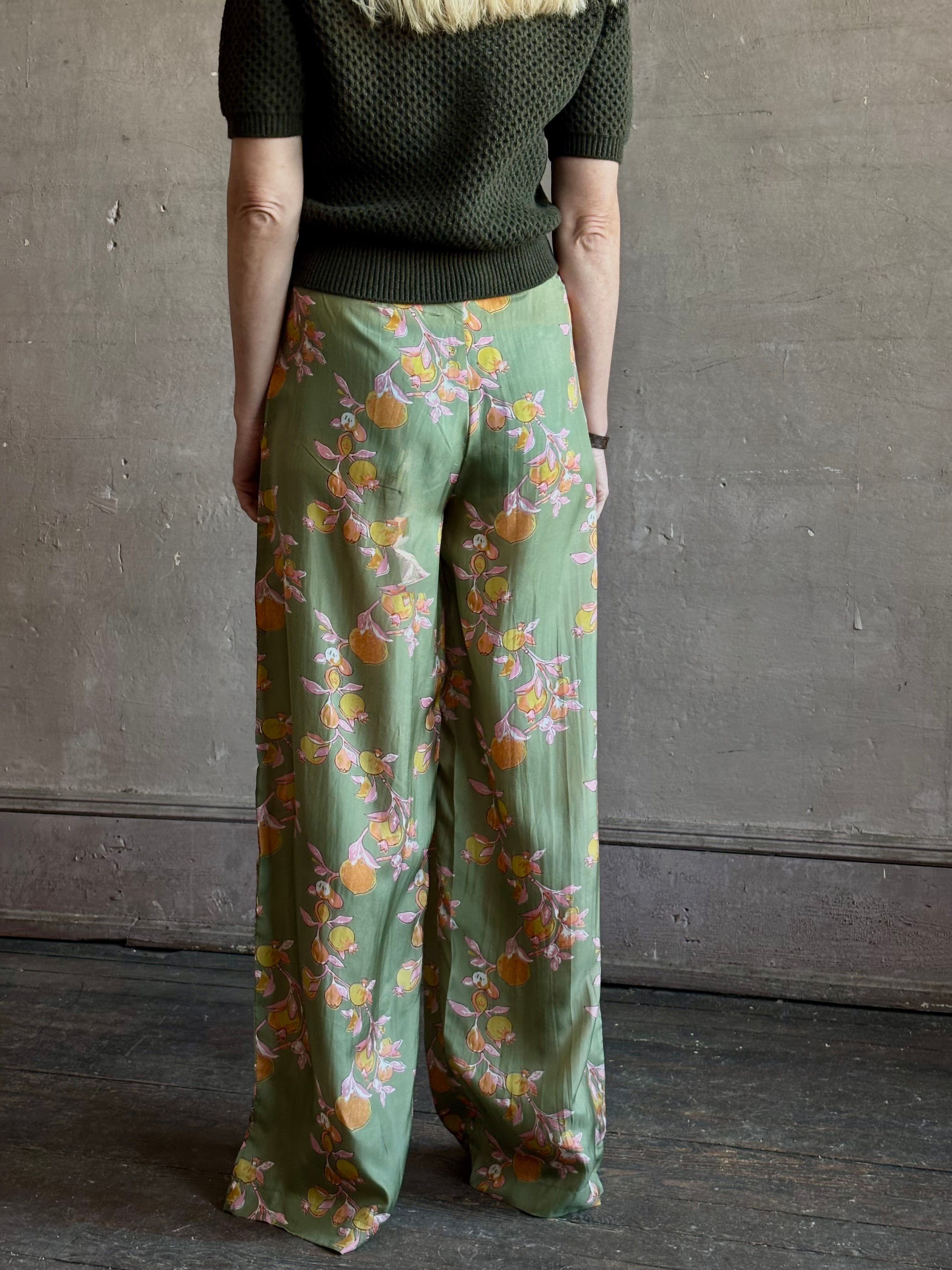 Mature woman wearing Hannah Artwear Azra silk Pant Khaki habotai with vibrant pomegranate print relaxed straight leg Fluid artisan-printed 