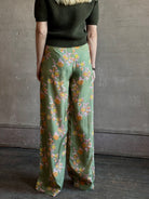 Mature woman wearing Hannah Artwear Azra silk Pant Khaki habotai with vibrant pomegranate print relaxed straight leg Fluid artisan-printed 