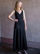 Image featuring a woman wearing the black tie Ivie paneled silp dress by Halston with a v neckline, spaghetti straps, and intricate diagonal seam detailing.