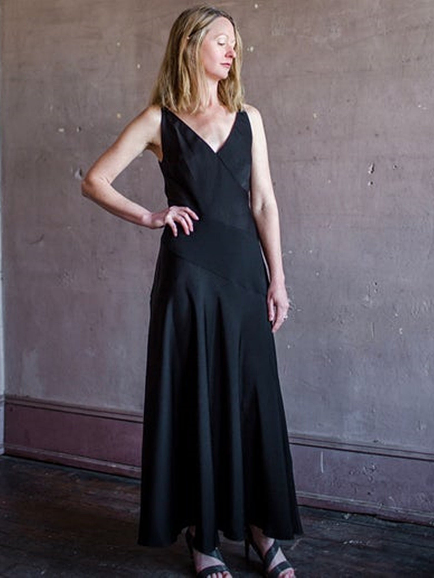 Image featuring a woman wearing the black tie Ivie paneled silp dress by Halston with a v neckline, spaghetti straps, and intricate diagonal seam detailing.