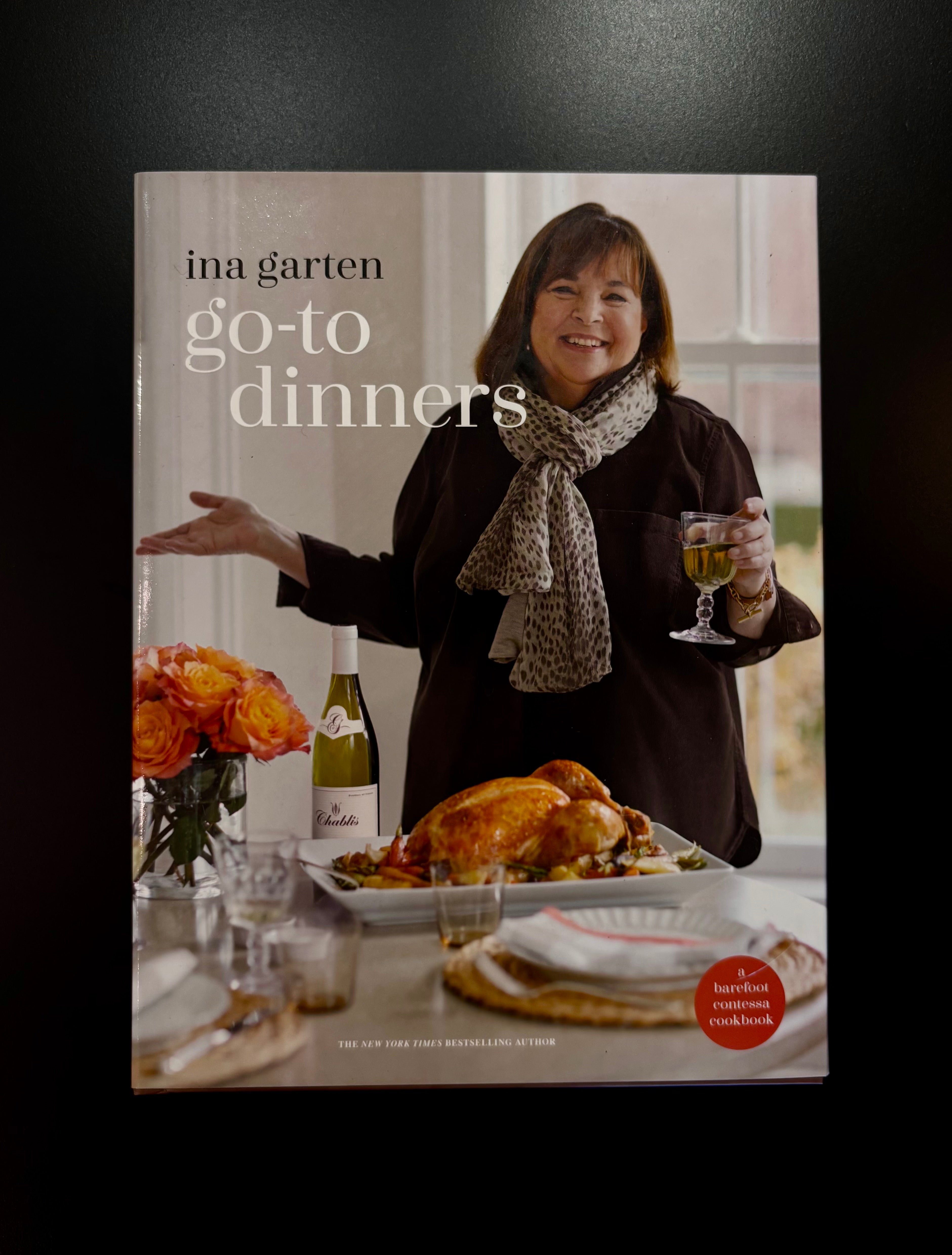 image of 'Go-To Dinners' cookbook by Ina Garten, featuring Ina holding a glass of white wine next to a roasted turkey 