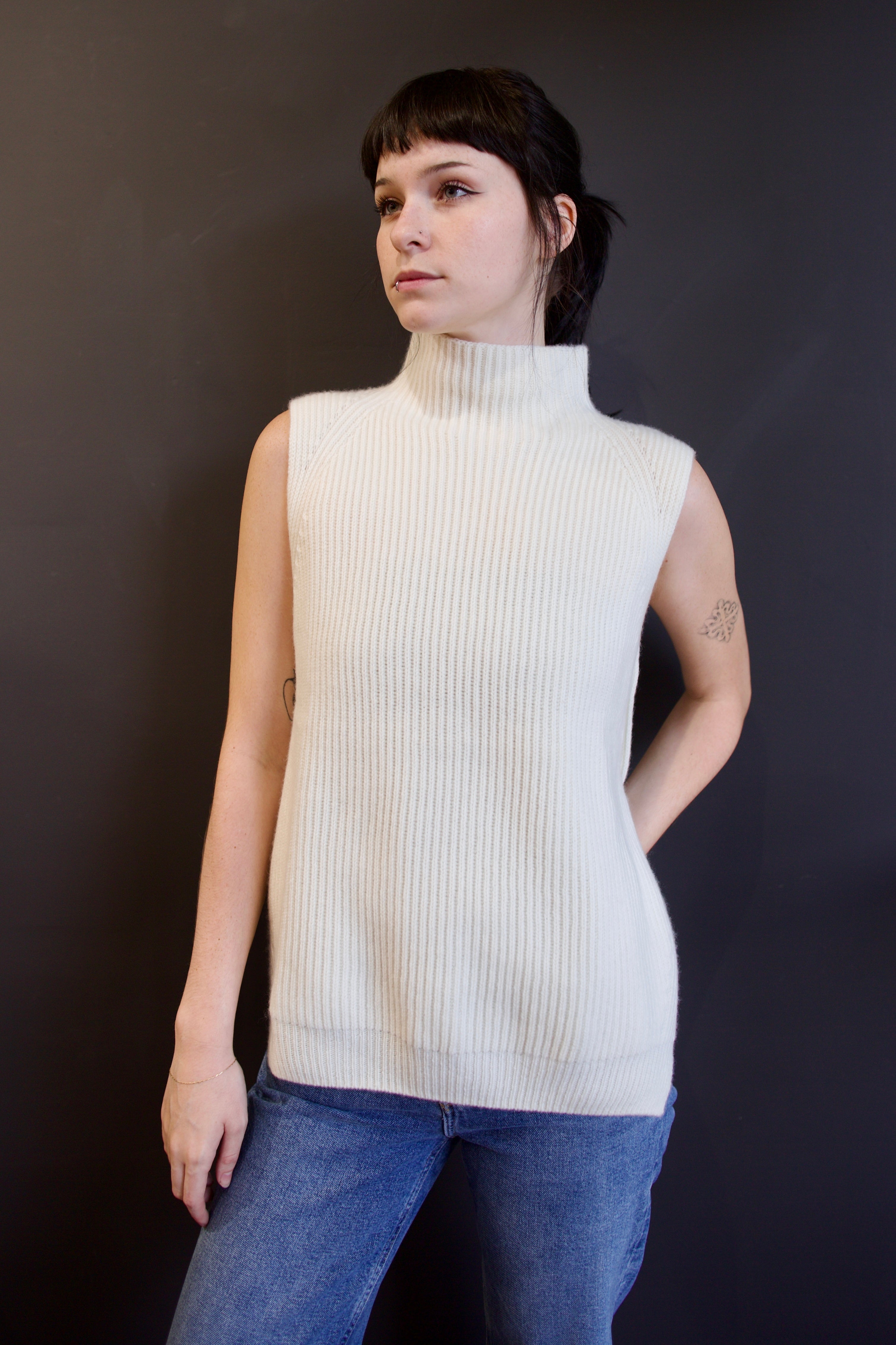 Model wearing luxury Kujten Erika cream-colored sleeveless cashmere sweater  with a mock neck and beautifully crafted