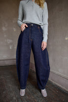 Model wearing dark blue Rachel Comey barrel jeans and a gray TWP cashmere henley sweater 
