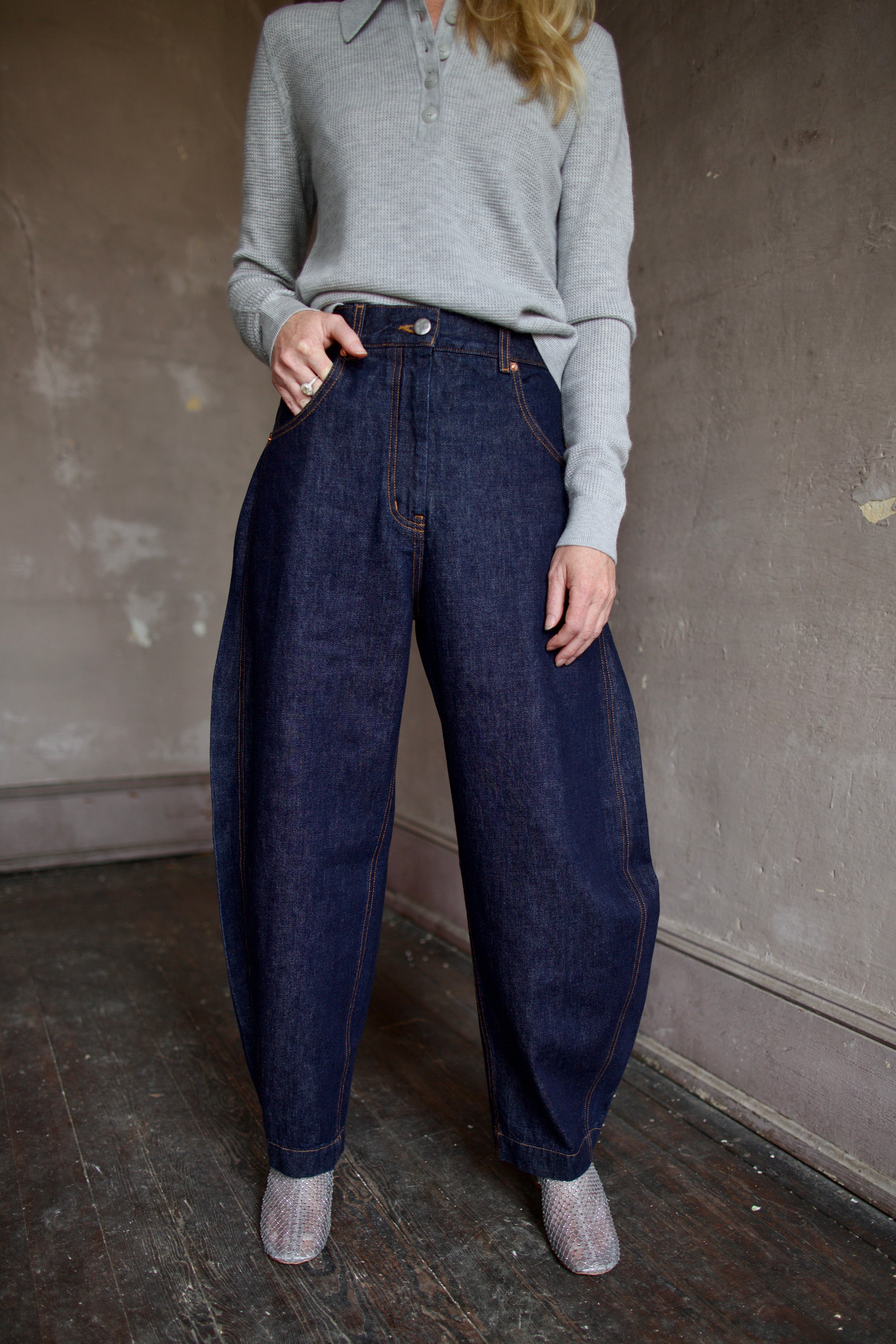 Model wearing dark blue Rachel Comey barrel jeans and a gray TWP cashmere henley sweater 