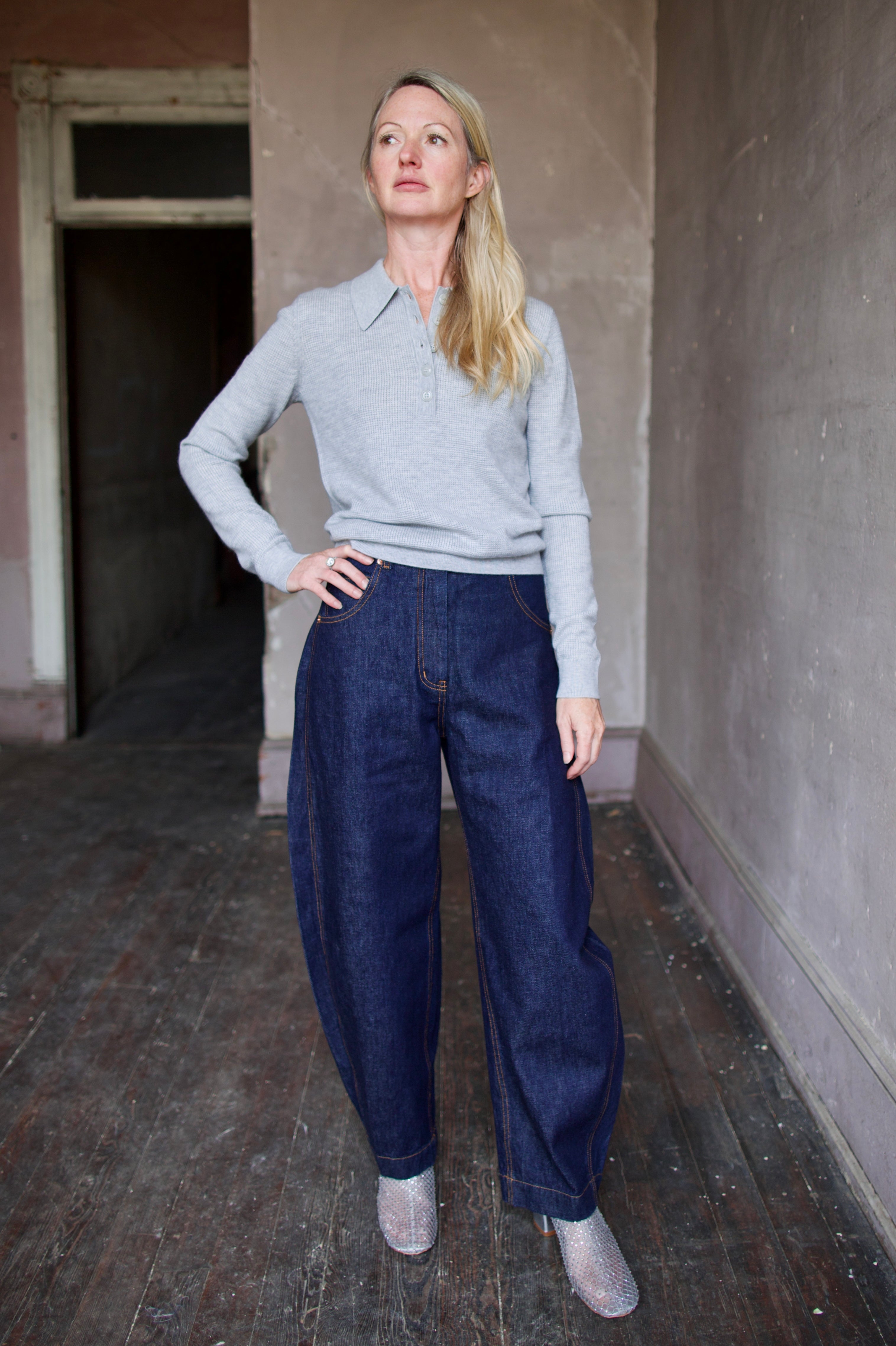 Mature model wearing dark blue Rachel Comey barrel jeans and a gray TWP cashmere henley sweater 
