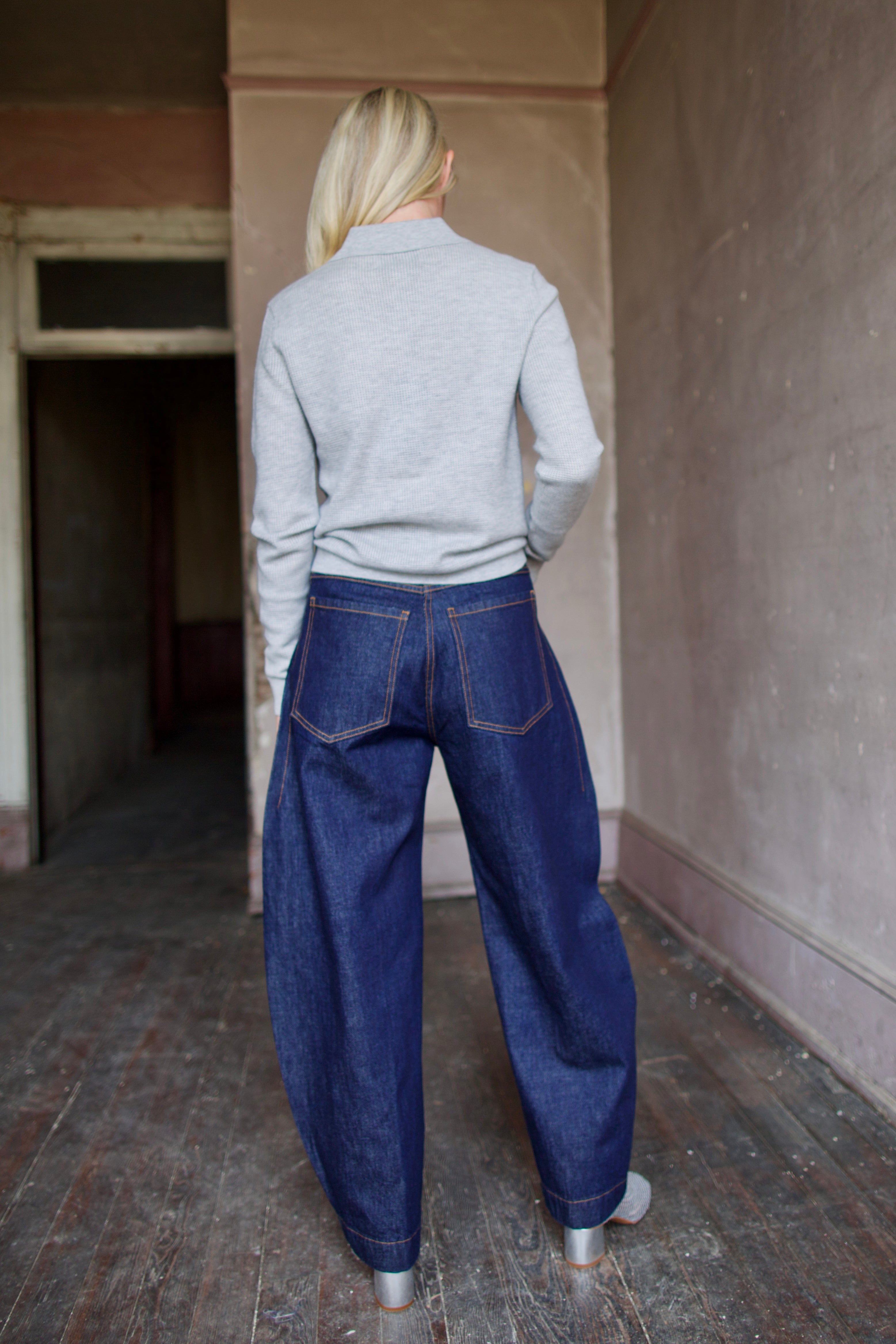 Mature model wearing dark blue Rachel Comey barrel jeans and a gray TWP cashmere henley sweater 