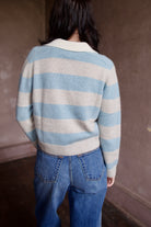 Woman wearing luxury brand Kujten Royce striped long sleeve cashmere polo sweater in light blue and grey