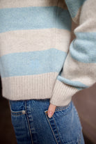 Woman wearing luxury brand Kujten Royce striped long sleeve cashmere polo sweater in light blue and grey