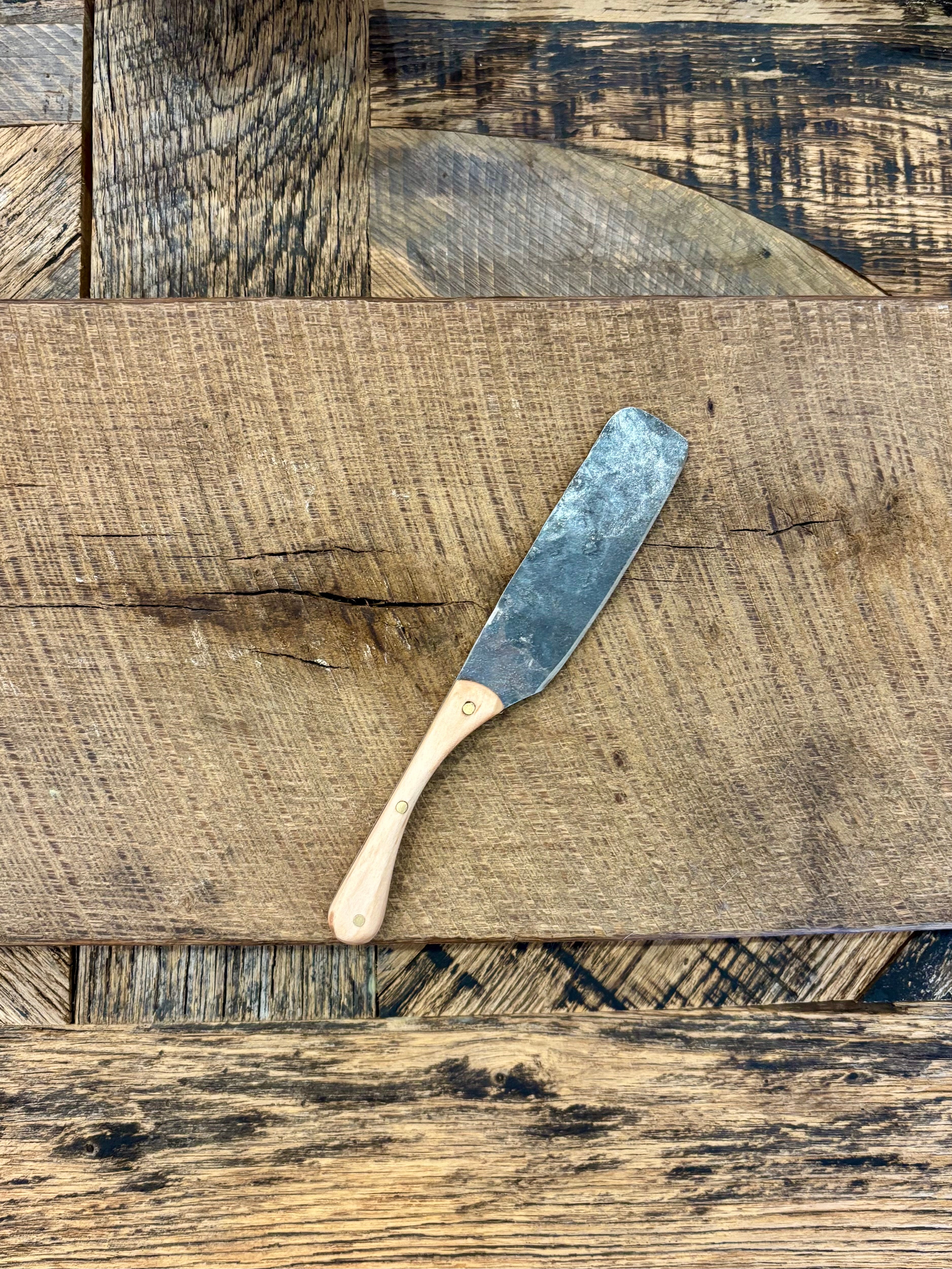 A rustic handcrafted charcuterie serving knife with a hand forged steel blade and  wooden maple handle made in USA