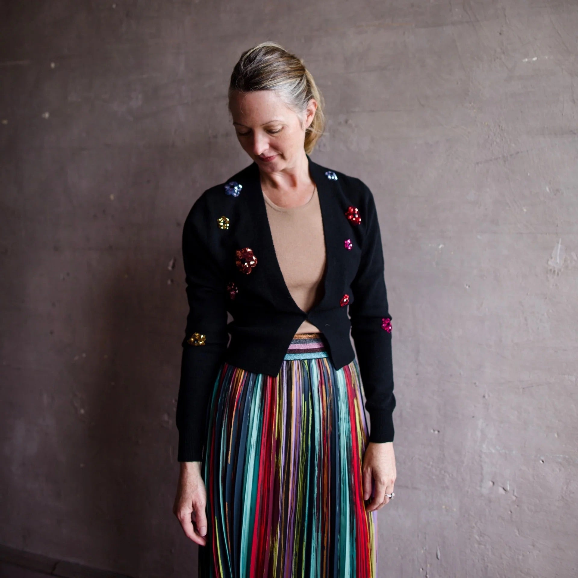 Image featuring a woman wearing the black Le Superbe pismo sequin flower luxurious cashmere cardigan with a  front closure and floral sequin embellishments. 