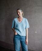 Image featuring a woman wearing the Lovisa sweater by Lisa Yang with a v neckline, short sleeves and in the softest powder blue brushed cashmere.