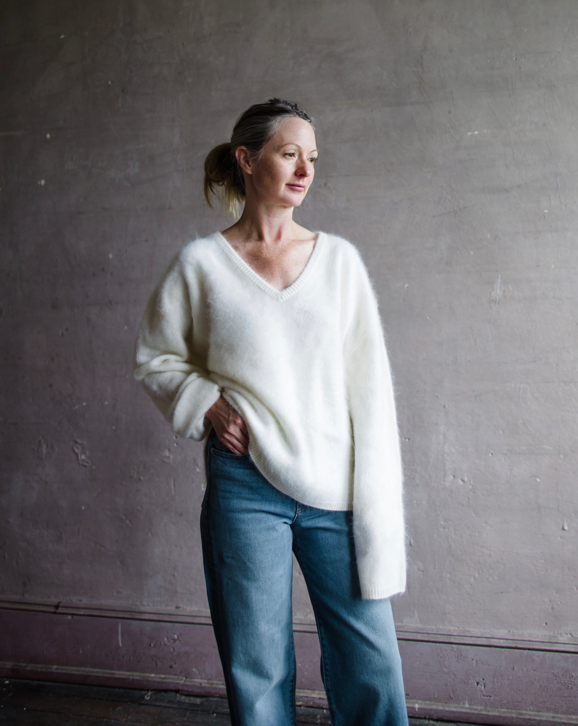 Image featuring a woman wearing the Margareta sweater by Lisa Yang with a deep v neckline, exaggerated sleeves in the softest ivory brushed cashmere.