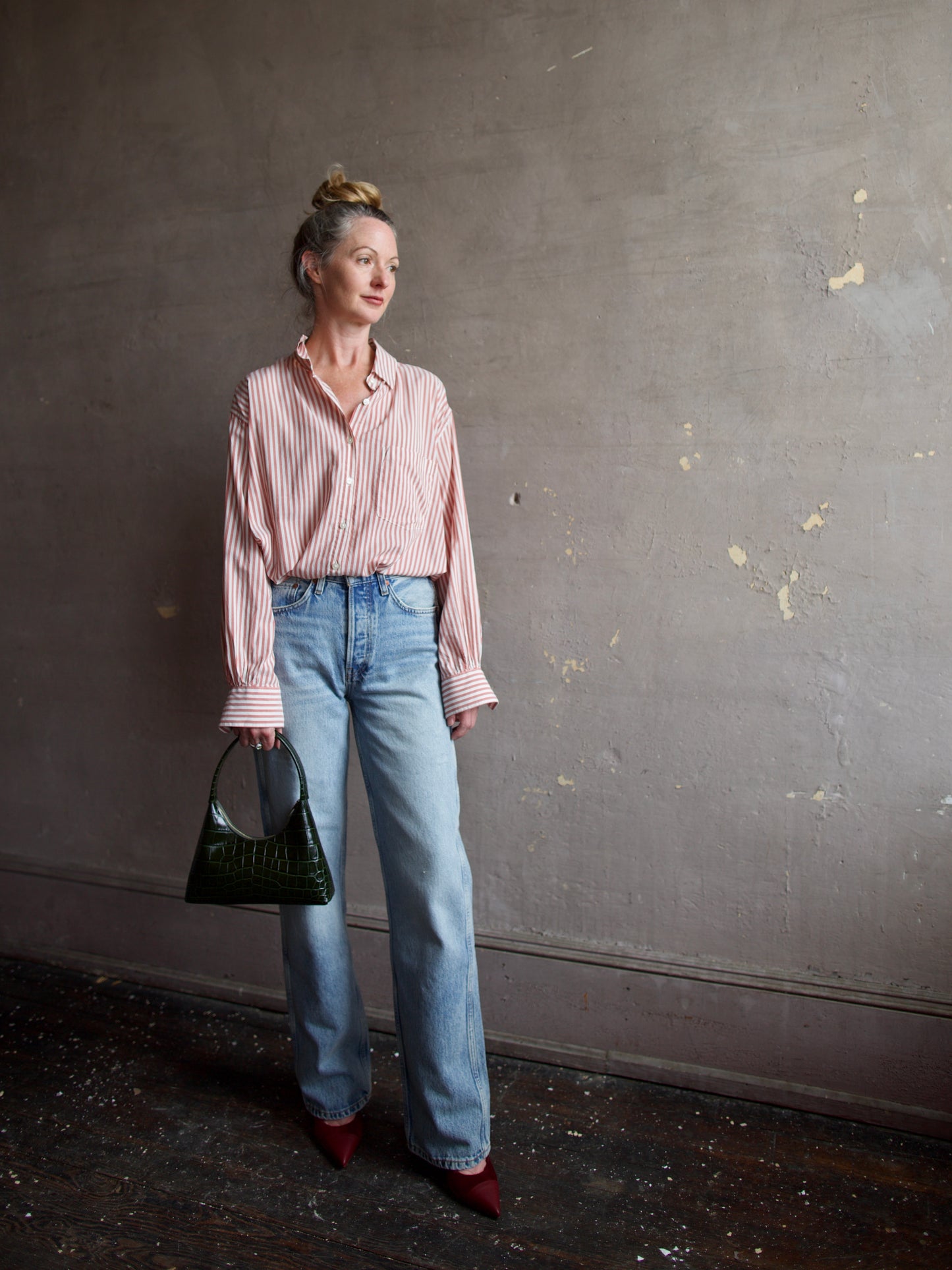 Image featuring a woman carrying the Mini Candy handbag by Mansur Gavriel in deep green with a gold finish zip closure and a croc texture.