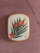 A rectangular ceramic tile featuring botanical pressed azaleas with green palm leaves on white clay