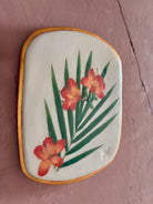 A rectangular ceramic tile featuring botanical pressed azaleas with green palm leaves on white clay