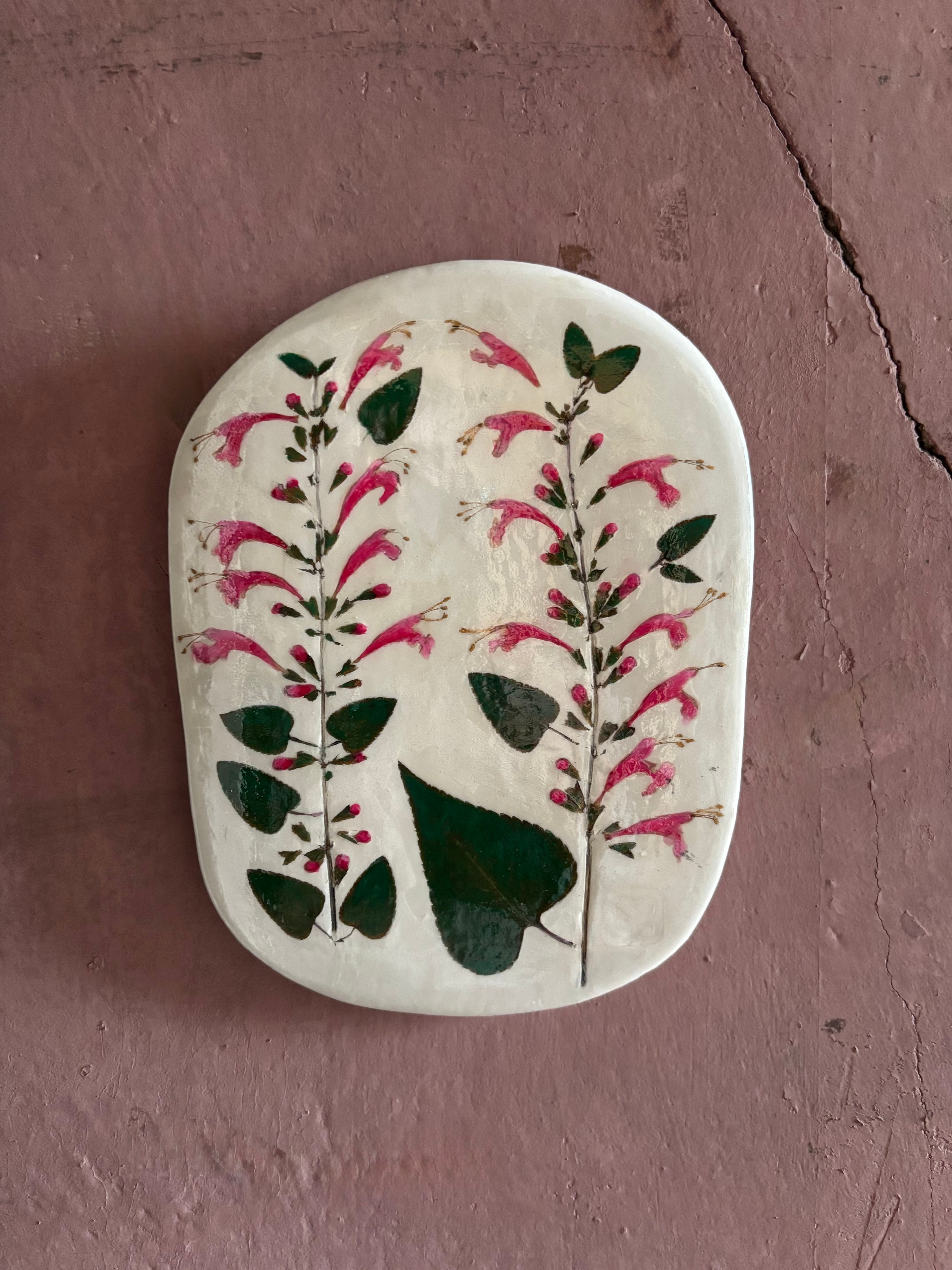 An oval ceramic tile with botanical black currant sage leaves pressed into cream-colored clay and air dried NC art